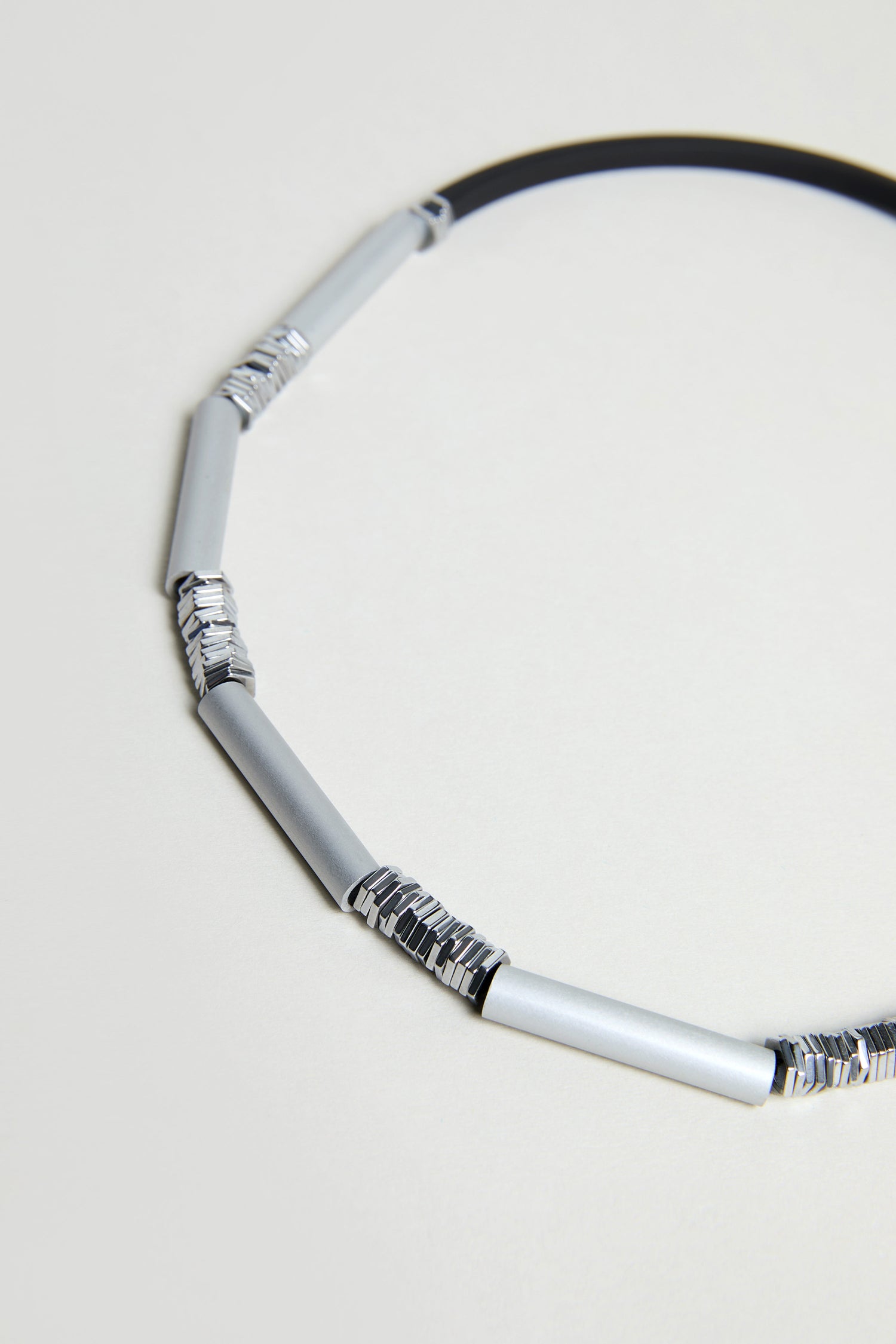 A close-up of the Silver Aluminium Hematite Necklace by Christina Brampti, with alternating silver cylindrical and textured anodised aluminium segments, shown on a plain background.