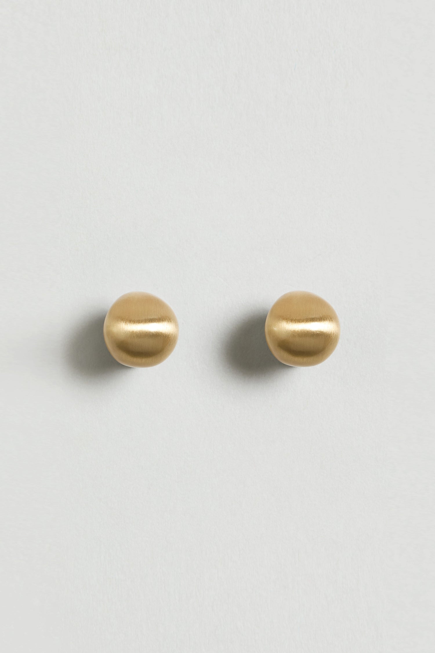 The Gold Plated Mini Pebble Earrings are a pair of sculptural earrings, each designed as elegant gold-plated balls.