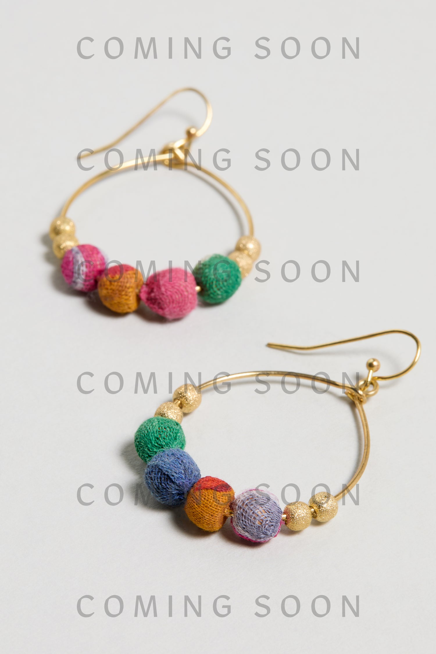 Kantha Gilded Hoop Earrings feature gold hoops adorned with colorful fabric and gold beads, displayed on a light surface. "COMING SOON" is repeated across the image.