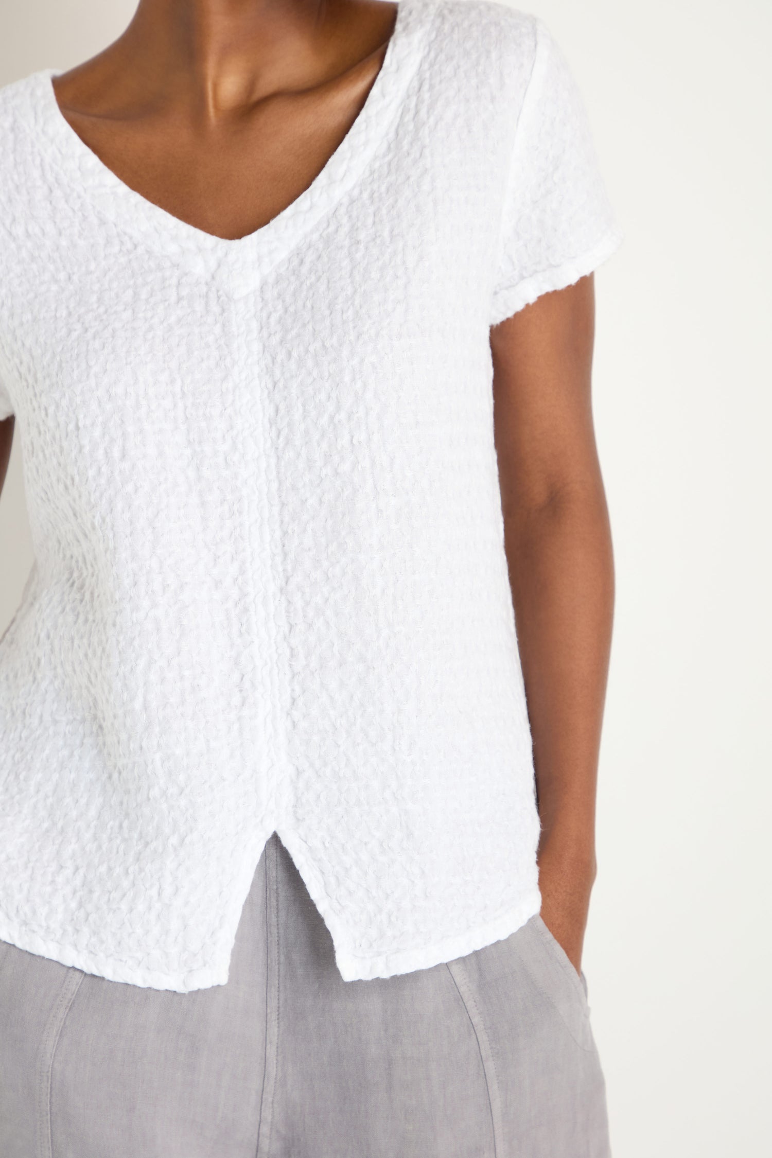 A close-up of a woman's body, highlighting the subtle detailing of the Waffle Linen V Neck Top.