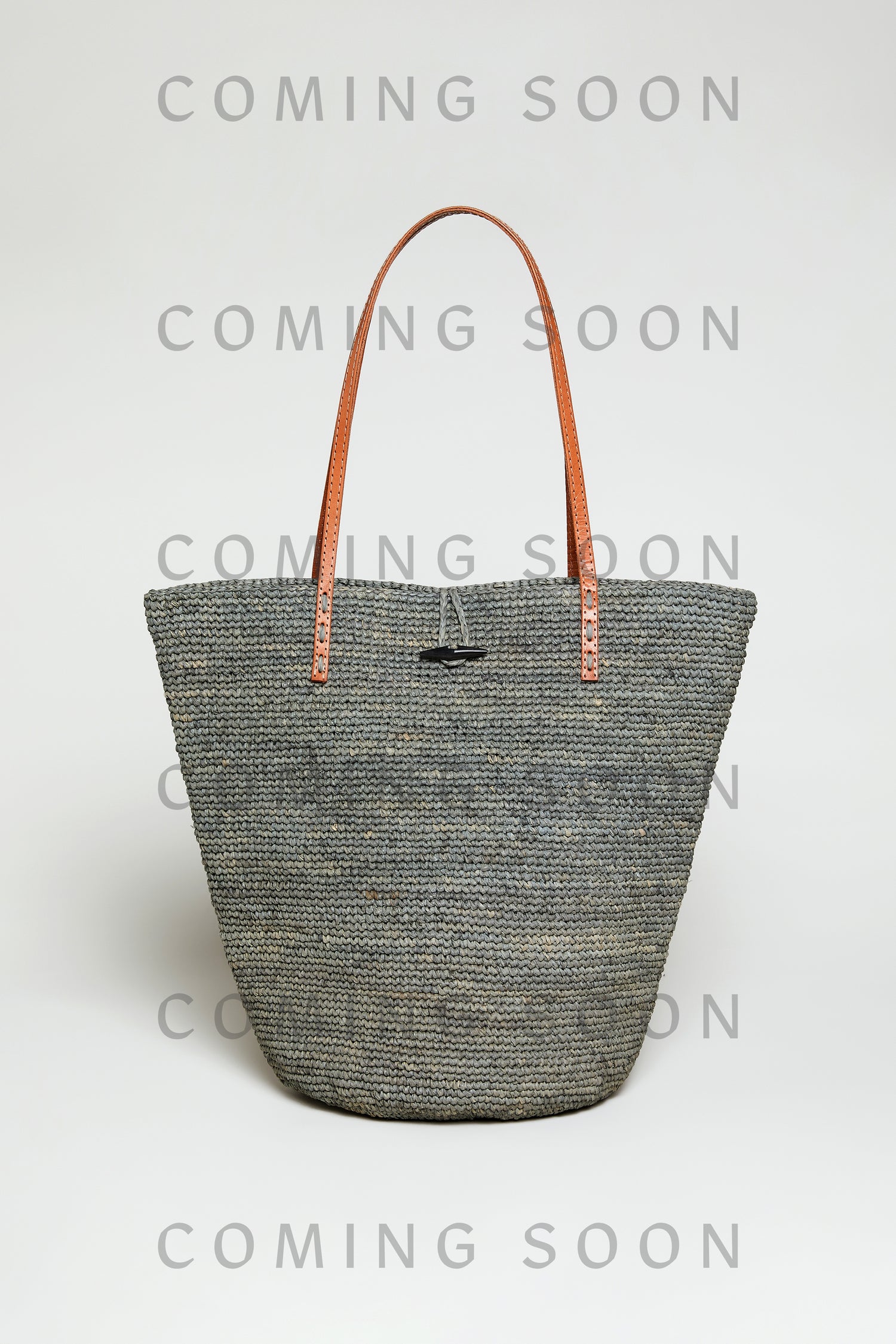 The Ilana Raffia Basket, a large woven gray tote with brown leather handles, is shown on a plain light background with "COMING SOON" displayed over the image.