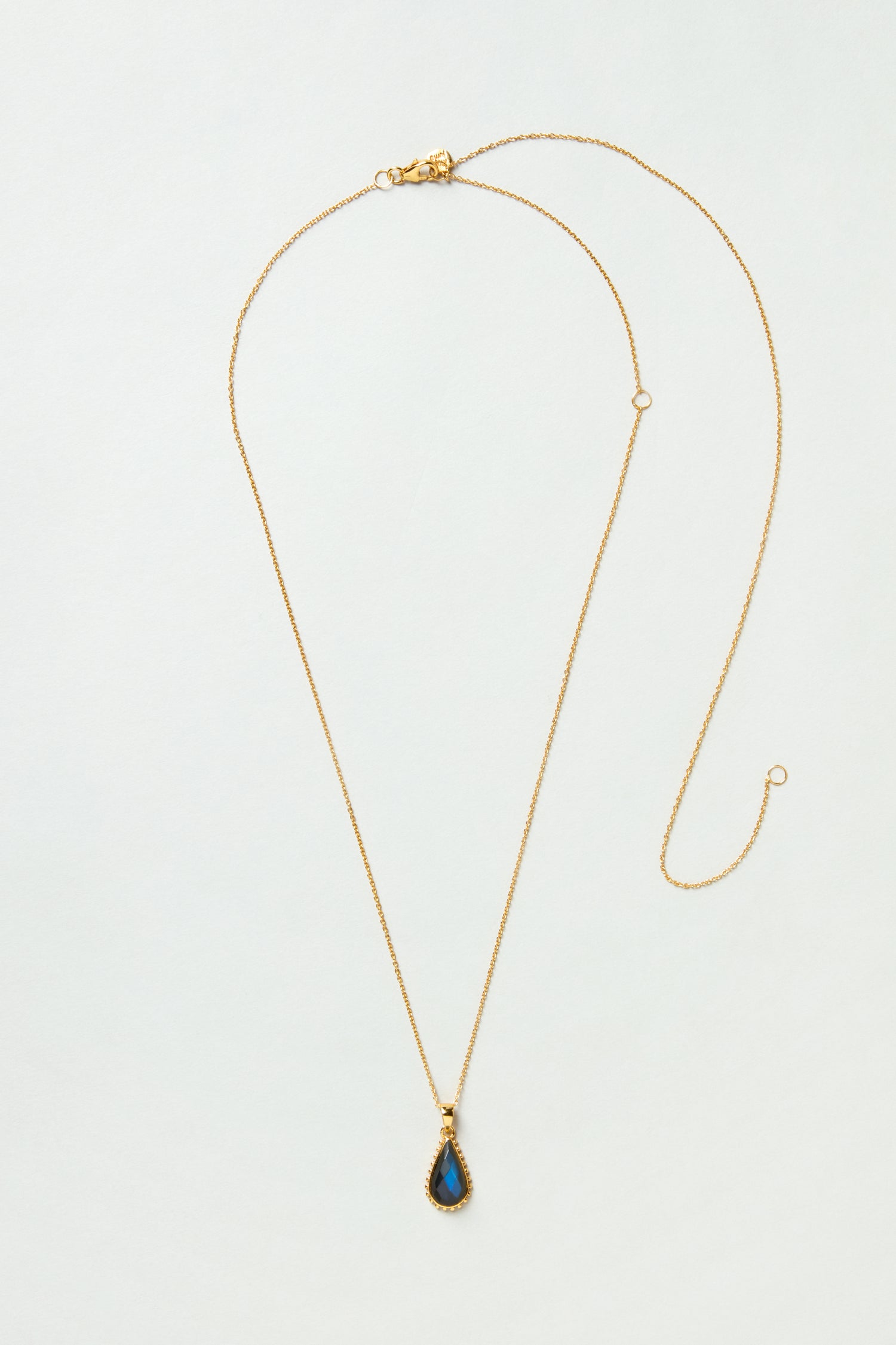The Gold Plated Labradorite Teardrop Necklace features a teardrop-shaped labradorite pendant on a gold chain, elegantly displayed on a light background.