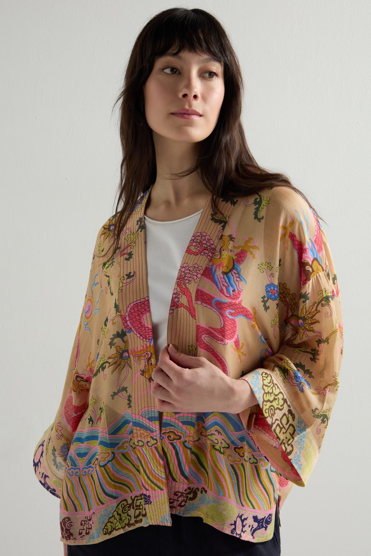 Dressed in a Dragon Print Kimono featuring a vintage-inspired pattern, a person stands against a plain background.
