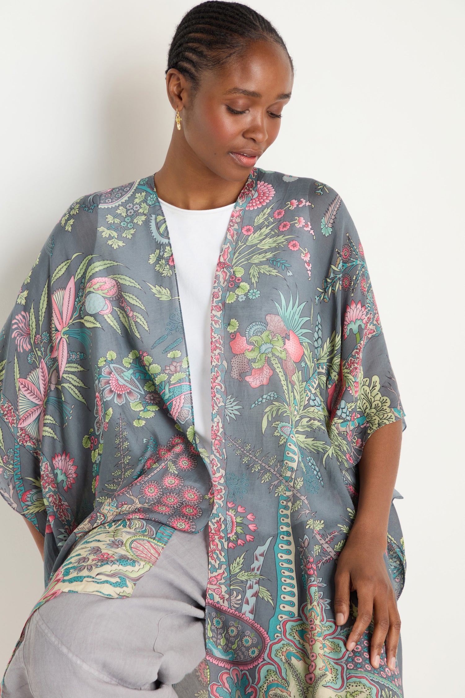 A woman wearing the Boho Garden Print Throwover over a white top and light gray pants looks down with a neutral expression.