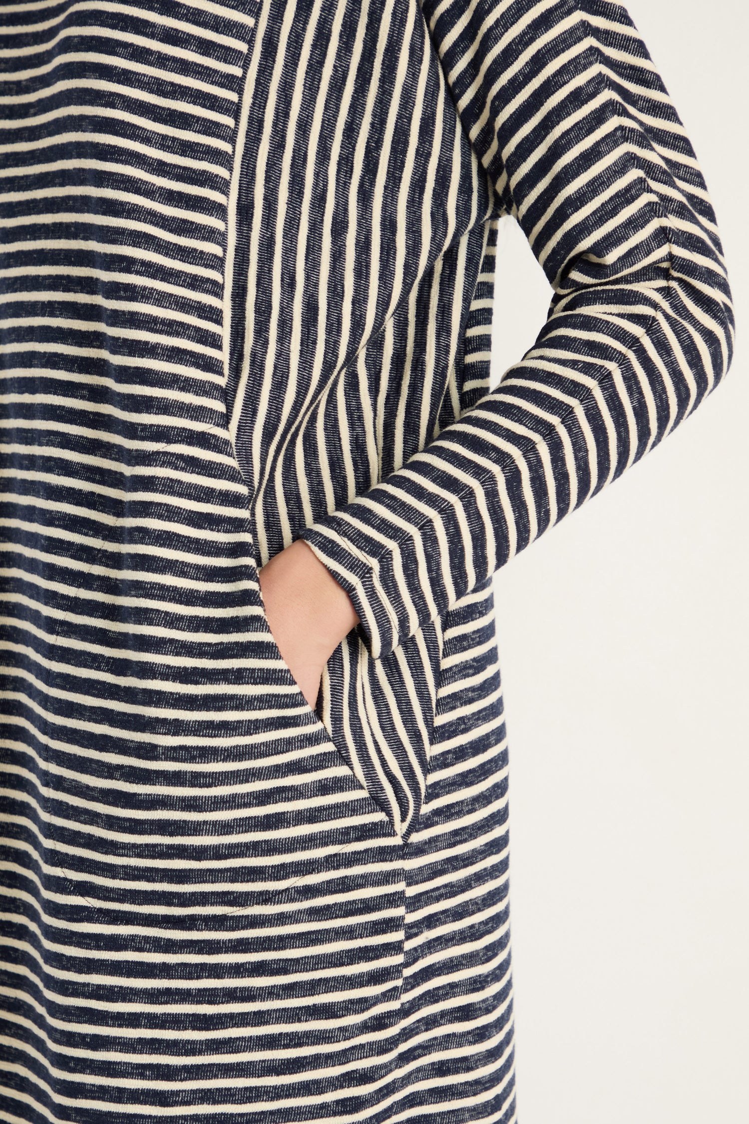 A person wearing the Textured Stripe Jersey Dress in navy and white, which features long sleeves, textured stripes, and a side pocket.