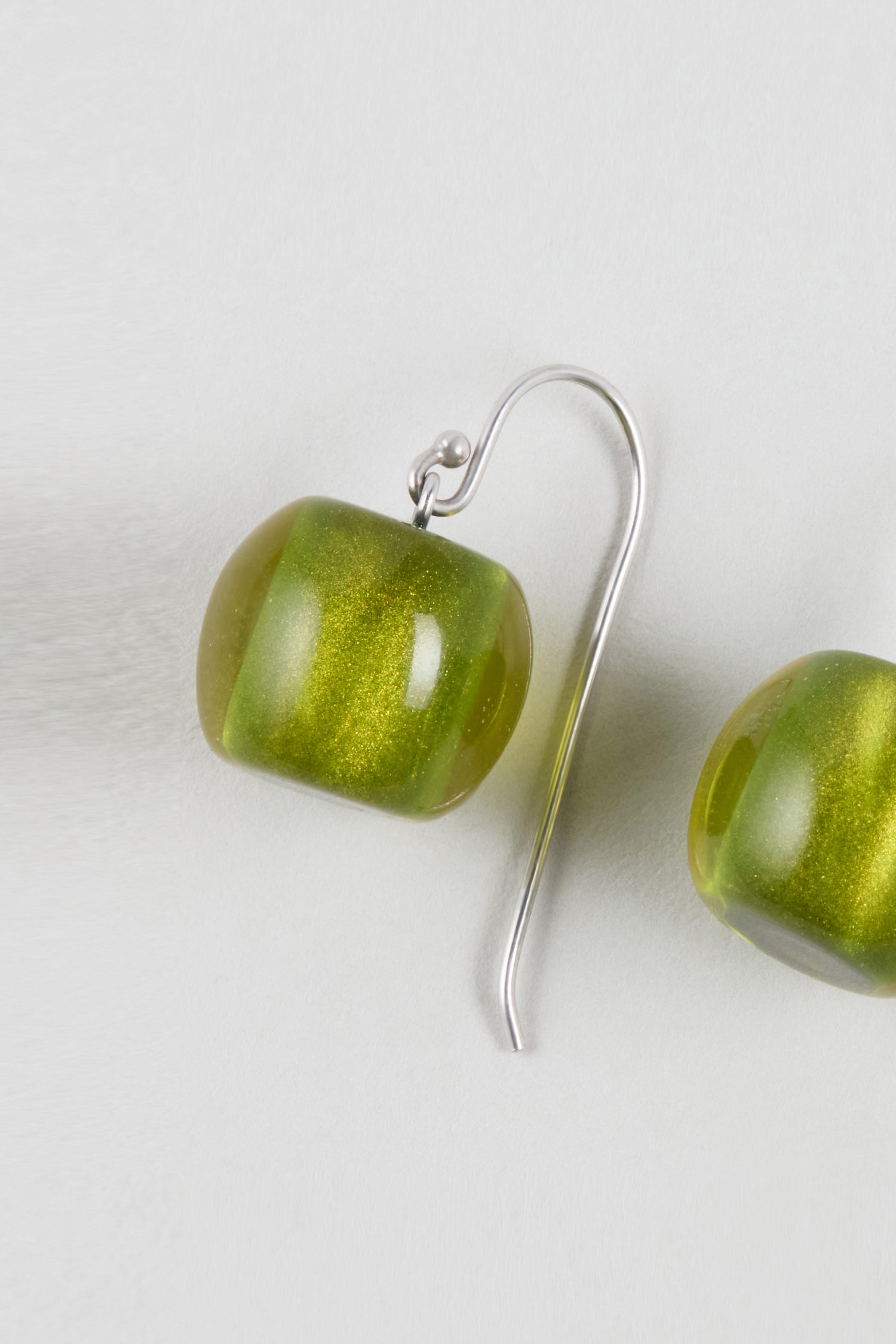 Close-up of a Colourful Bead Resin Earring with a green glass bead and silver hook on a light gray background, highlighting its contemporary jewellery style.
