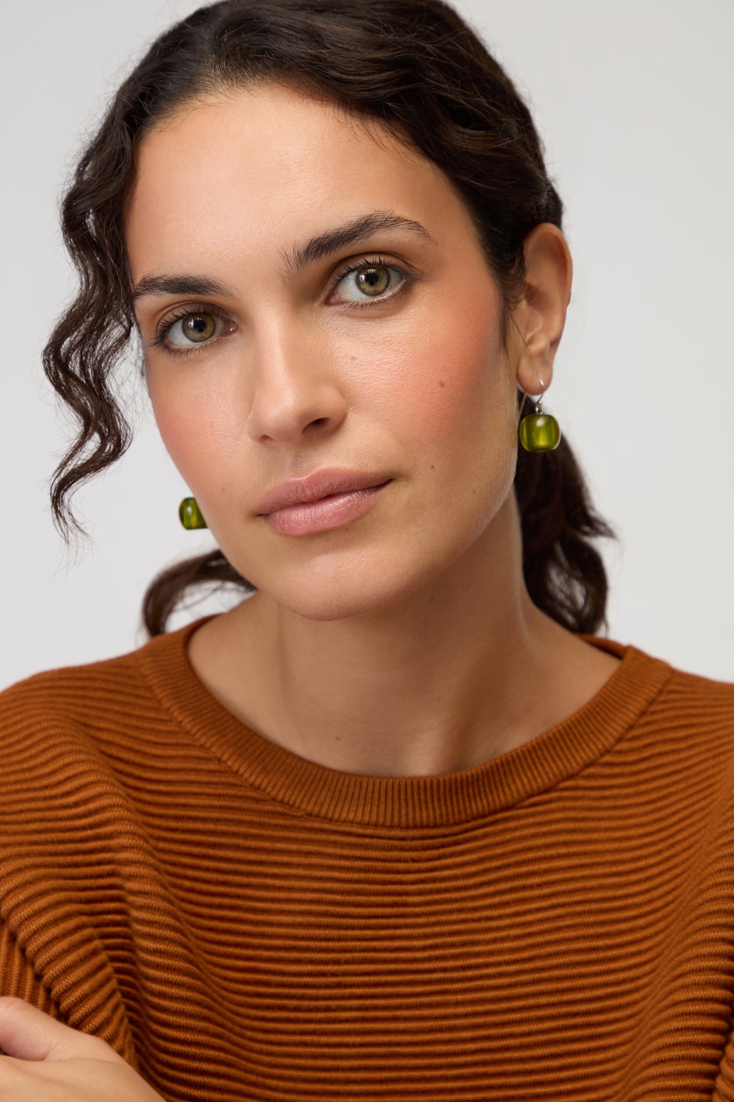 A woman with wavy brown hair and a rust ribbed top wears Colourful Bead Resin Earrings, looking directly at the camera and displaying her modern jewellery style against a plain background.
