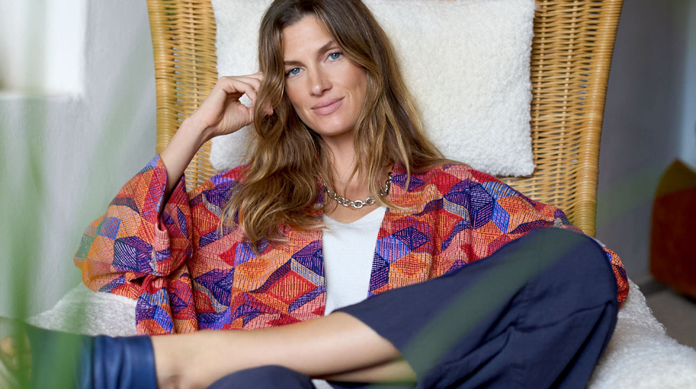 A woman sitting on a bed in a zebra print shirt.