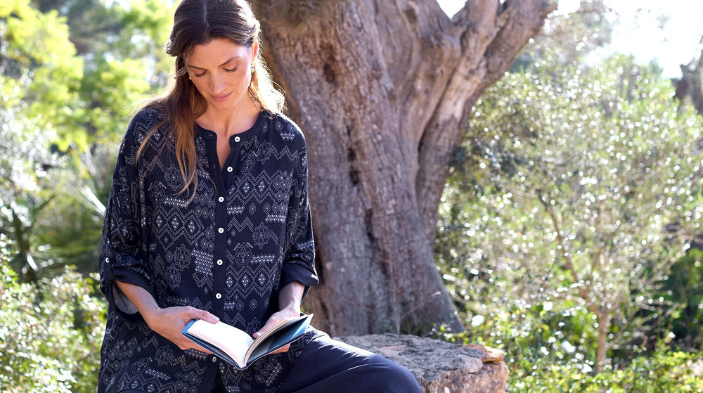 A woman leaning against a tree in a garden.