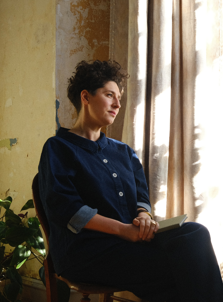 woman in a navy jumpsuit looking out a window