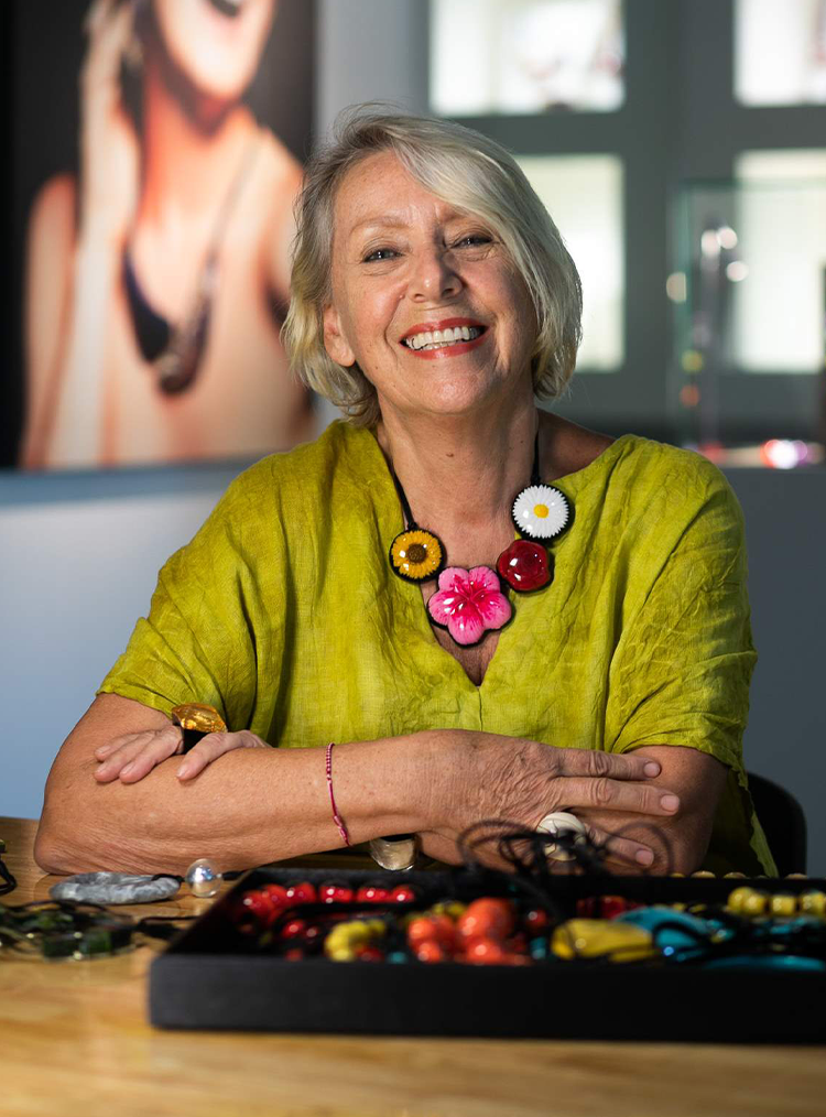 woman in a green tunic and statement necklace sat at a table