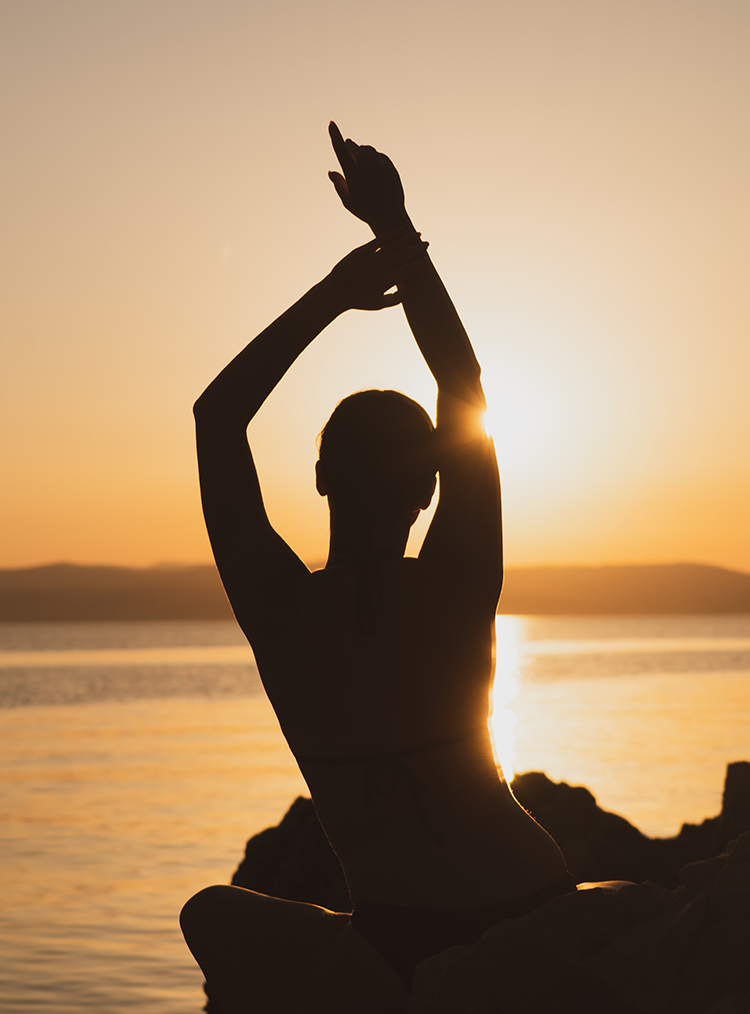 person stretching in front of a sunset