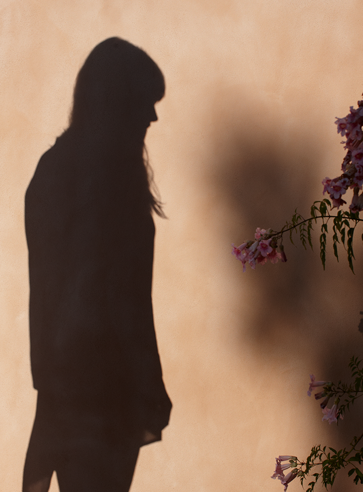 shadow of a woman against a peach coloured wall