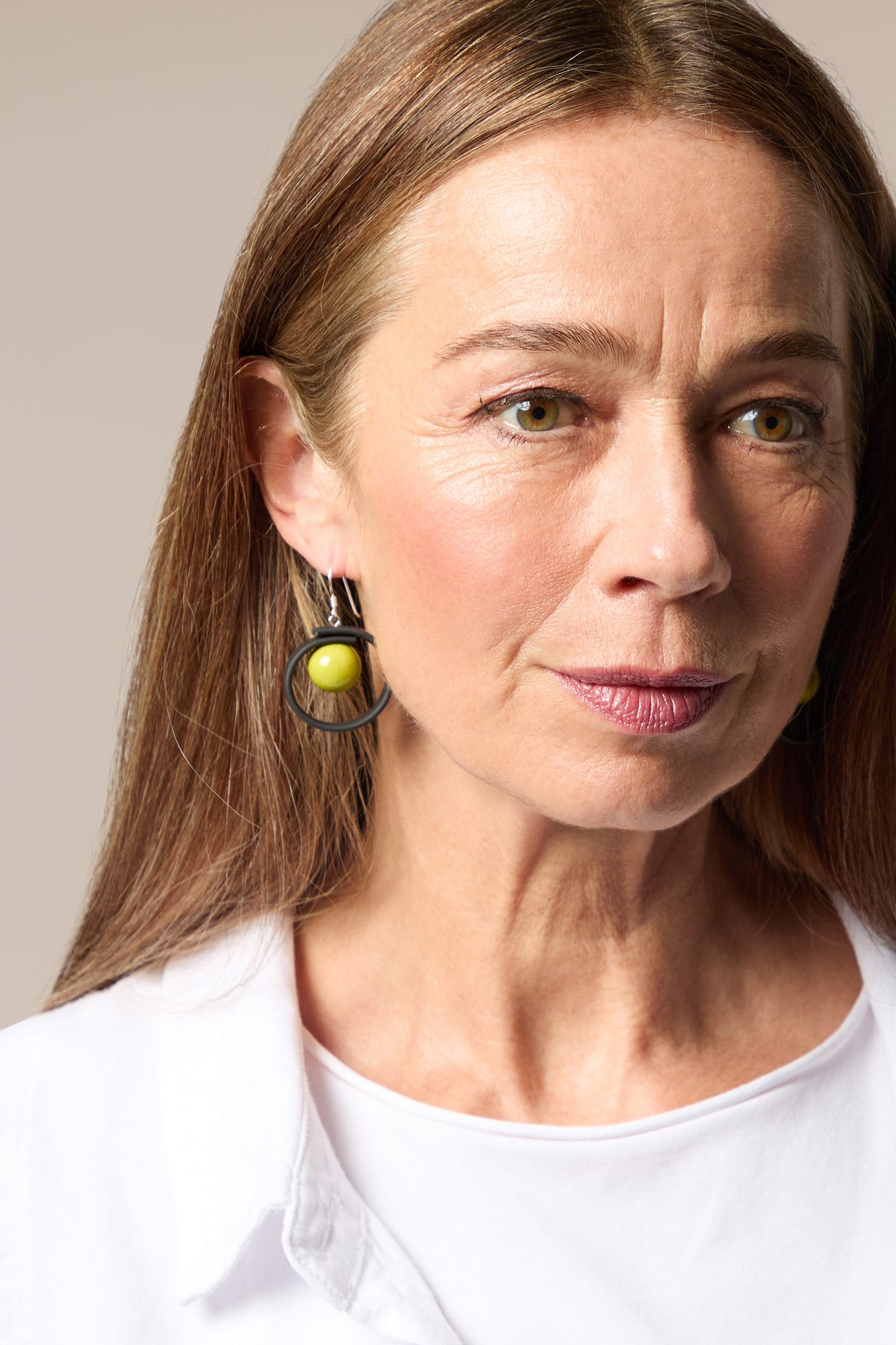 A woman showcasing her Tempo Earrings as she confidently wears her crisp white shirt.