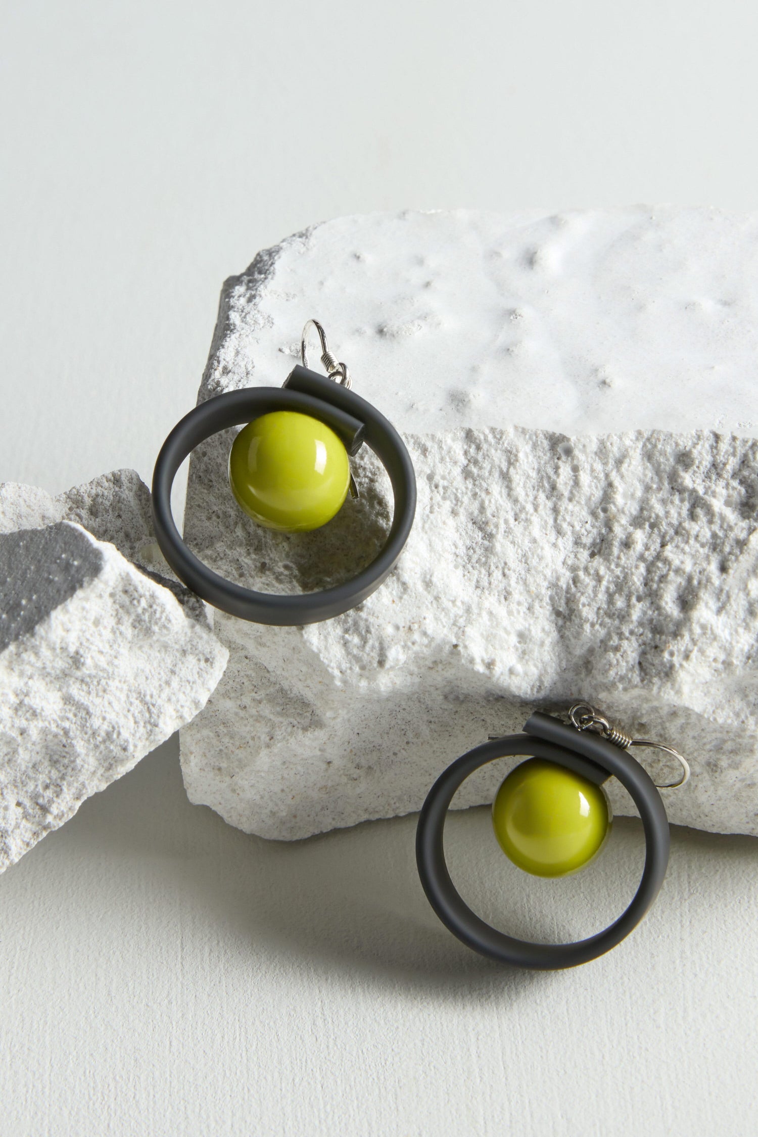 A pair of Tempo Earrings, crafted through jewellery making on a rock.