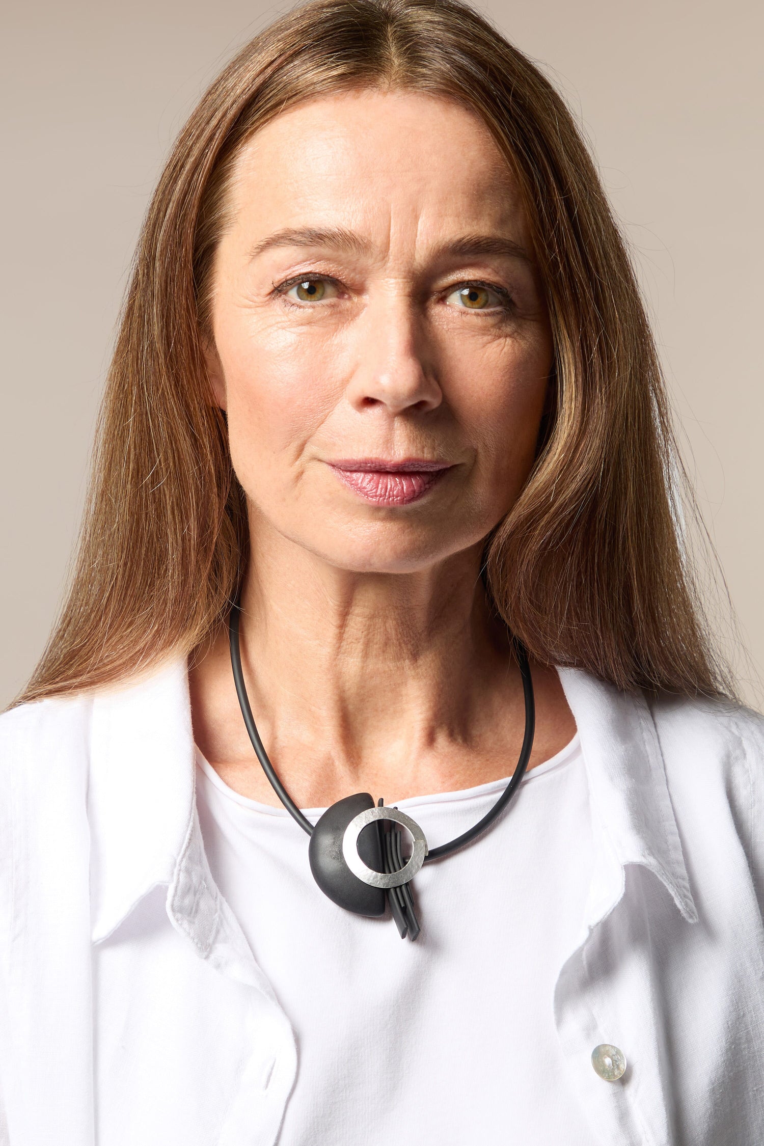 A woman in a white shirt with a Saturn Necklace featuring magnetic beads.