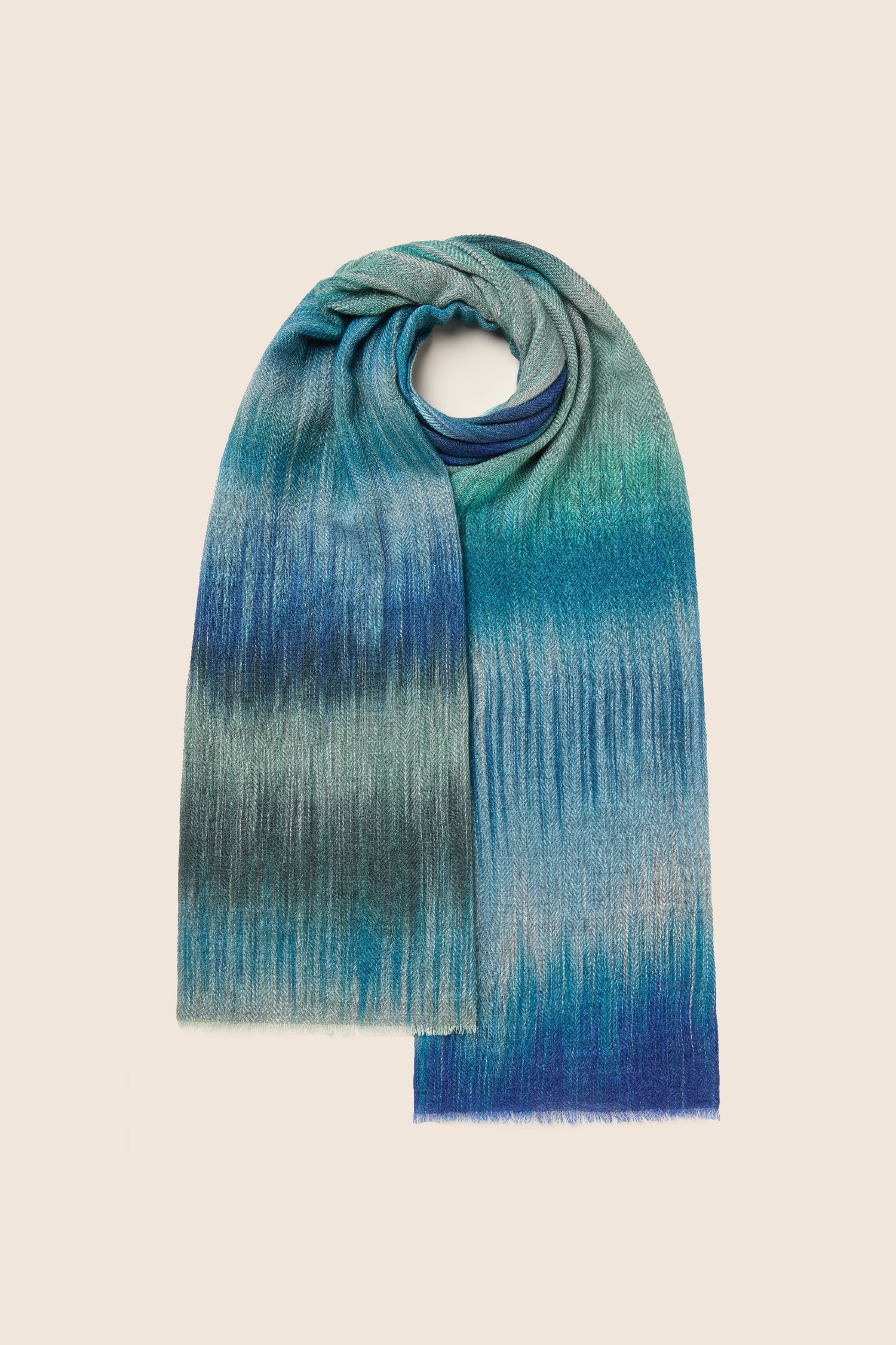 A Sky Wool Cashmere Blend Scarf, boasting a gradient pattern in shades of blue, green, and grey and featuring a ribbed texture with an ultra-soft touch, is arranged in a looped display.