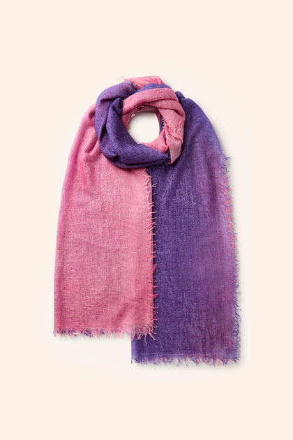 The Harmony Cashmere Scarf, a multi-tonal accessory displaying pink on the left and purple on the right, laid flat with frayed edges and a convenient loop at the top – an ideal addition to your autumn wardrobe.