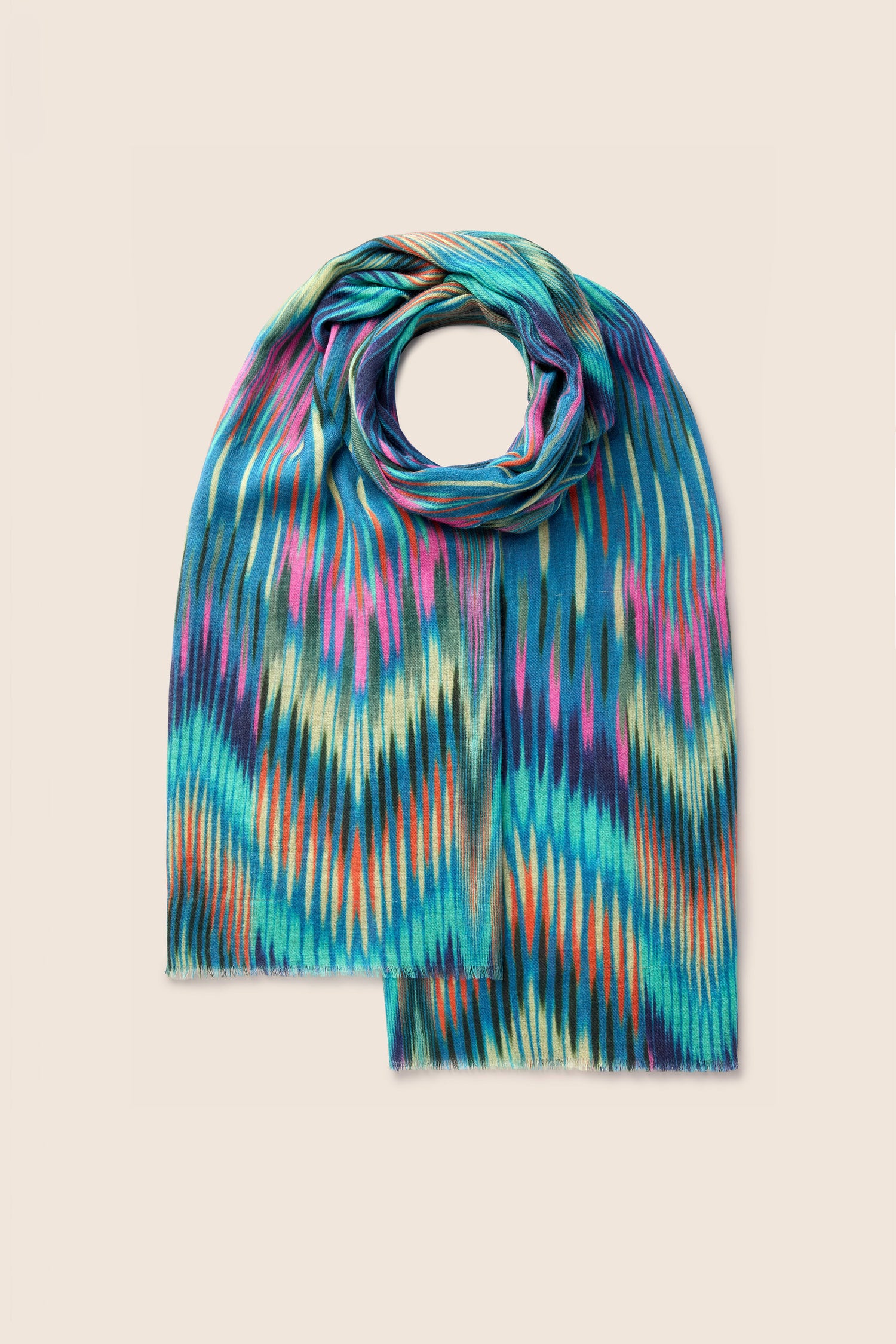 Introducing the Autumnal Ikat Wool Scarf: a vibrant accessory featuring a teal base adorned with zigzag patterns in blue, pink, orange, and yellow, all set against a beige background. Its ikat-inspired print and autumnal hues make it the perfect addition to your seasonal wardrobe.