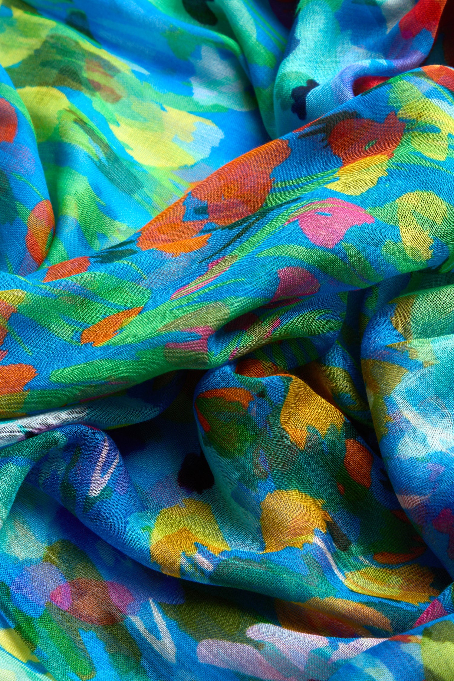 The Abstract Painted Garden Scarf is a lightweight accessory featuring a vibrant abstract pattern, simulating a painted garden with shades of blue, green, red, yellow, and orange in a paint stroke design.