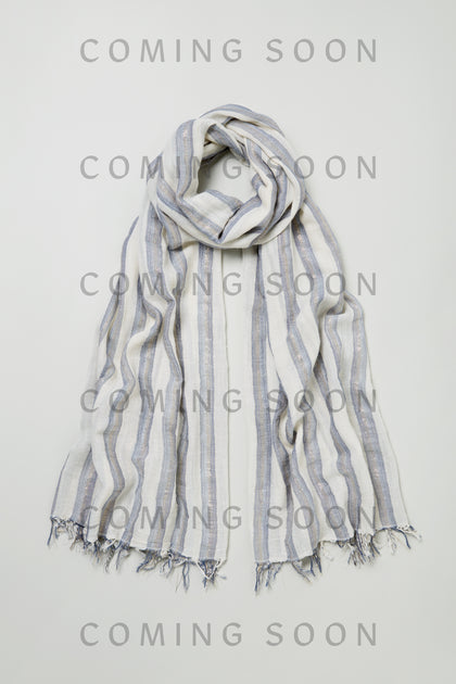 The Lurex Stripe Cotton Blend Scarf, a light-colored scarf with stripes and fringed edges, is displayed flat on a white background with "COMING SOON" in bold gray letters across the image.