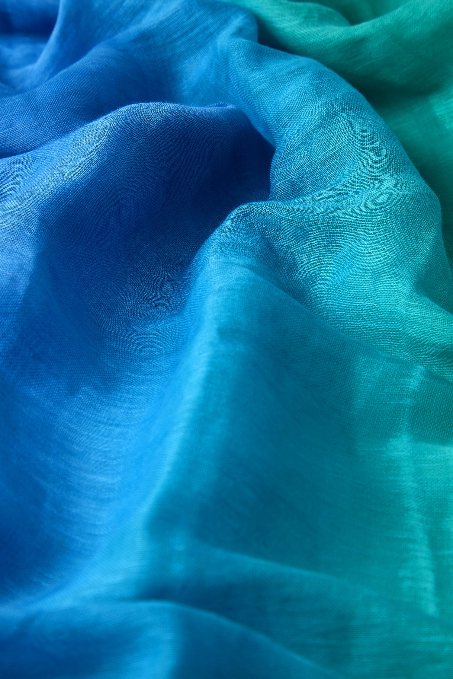 Detailed view of the Ombre Linen Mix Scarf featuring a wavy, flowing design that transitions from blue to green, emphasizing its textured and airy appeal.