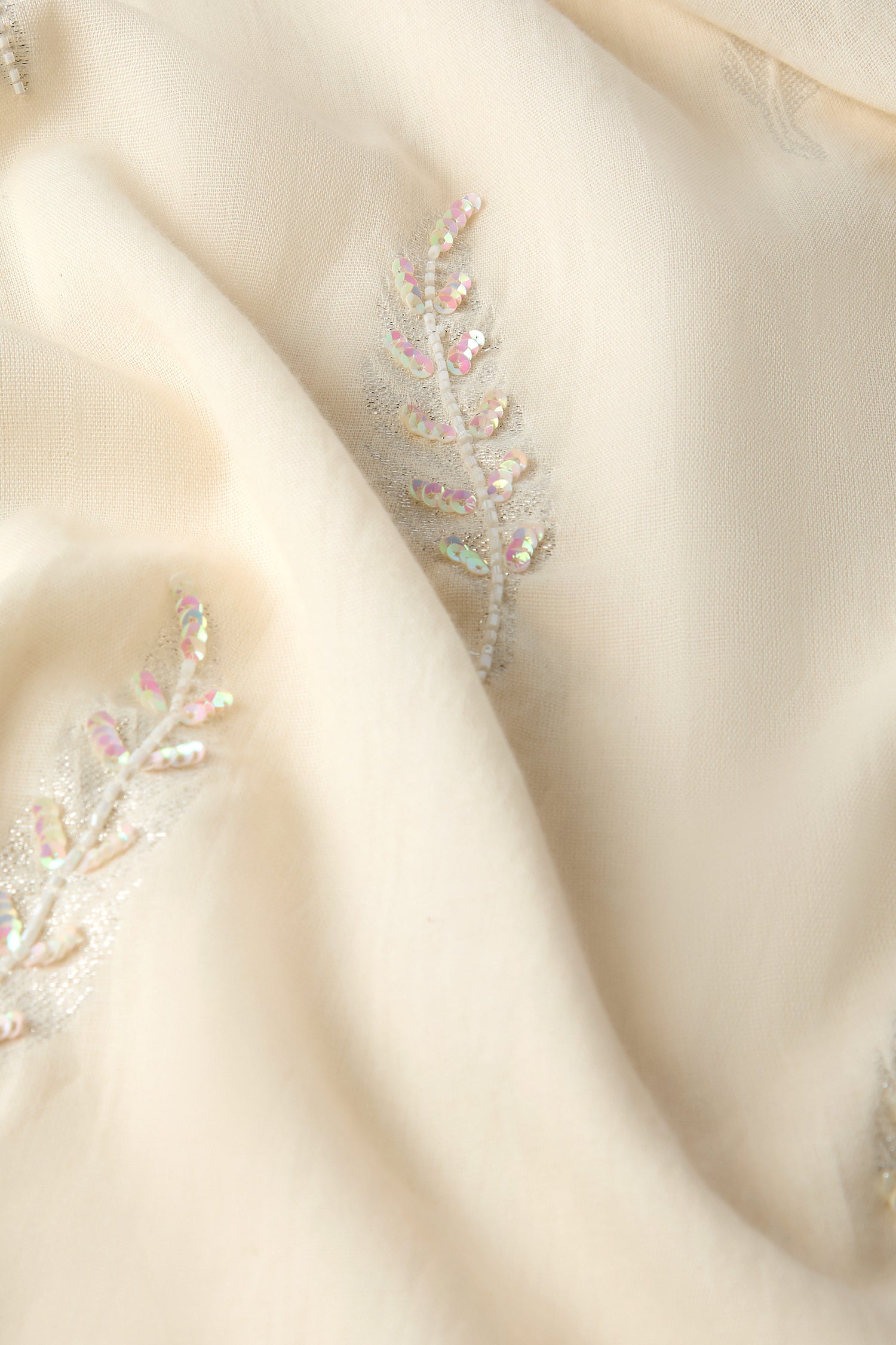 Cream-colored fabric adorned with silver and iridescent sequin leaf embroidery, ideal for a Hand Embroidered Feather Scarf.