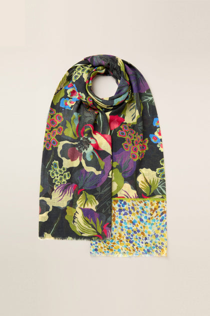 The Painted Garden Wool Mix Scarf, featuring a luxurious wool blend with a multicolored floral pattern that evokes the charm of a hand-painted botanical print, is neatly folded against a plain background.