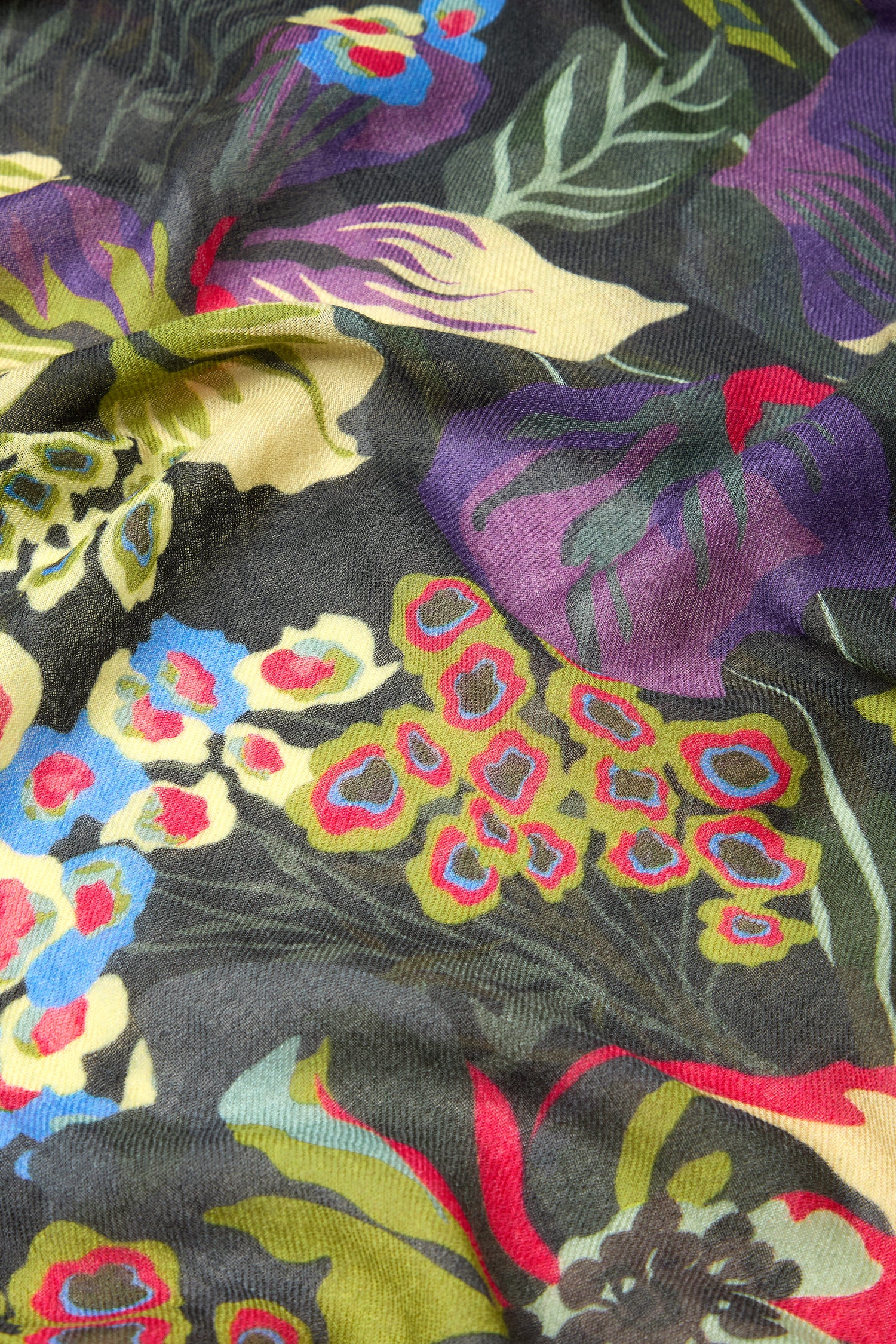 Close-up of the Painted Garden Wool Mix Scarf, showcasing a vibrant floral pattern with red, yellow, green, and purple flowers against a dark background.