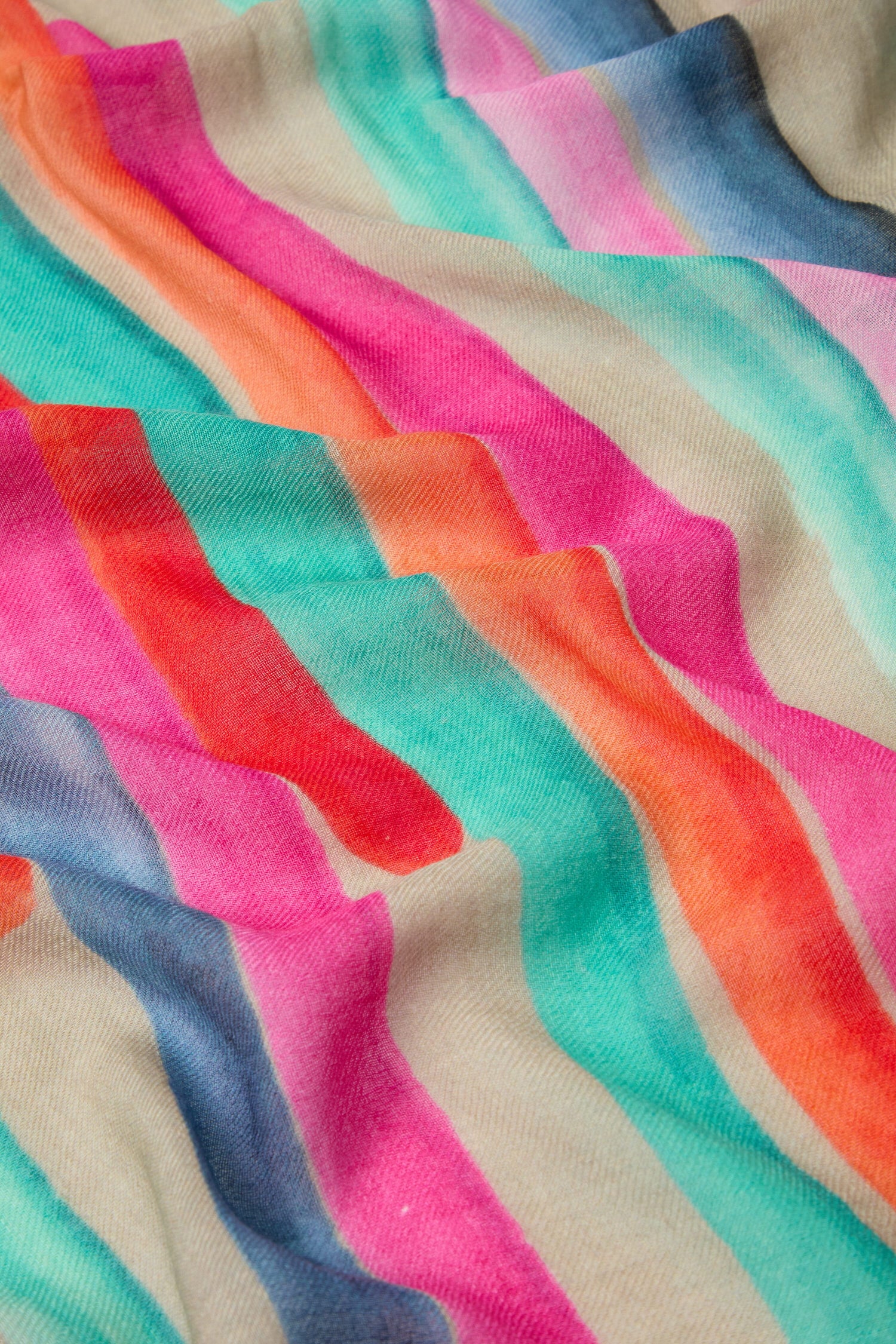 The Painterly Stripe Wool Mix Scarf features a vibrant design with brushstroke inspired stripes in an array of pink, orange, green, blue, and beige hues.