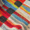 Close-up view of the Pianist Wool Mix Scarf, showcasing its colorful, striped fabric with various shades of red, blue, yellow, black, and white.