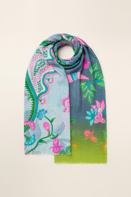 The Heavenly Garden Scarf is a vibrant accessory adorned with a floral and nature-inspired design, showcasing hues of blue, pink, green, and subtle hints of yellow. Made from lightweight fabric, this scarf is elegantly arranged in a loop.