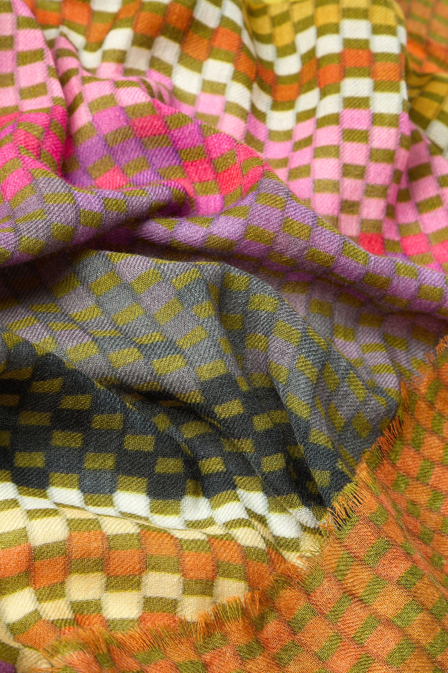 A close-up view showcases the Mini Squares Wool Scarf, made from 100% wool, featuring a checkered pattern in vibrant pink, yellow, orange, and green hues. The scarf appears folded and textured.