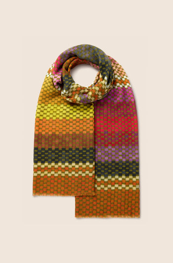 A Mini Squares Wool Scarf, adorned with a multicolored checkerboard pattern featuring gradient shades of orange, red, yellow, green, and purple, is displayed against a beige background.