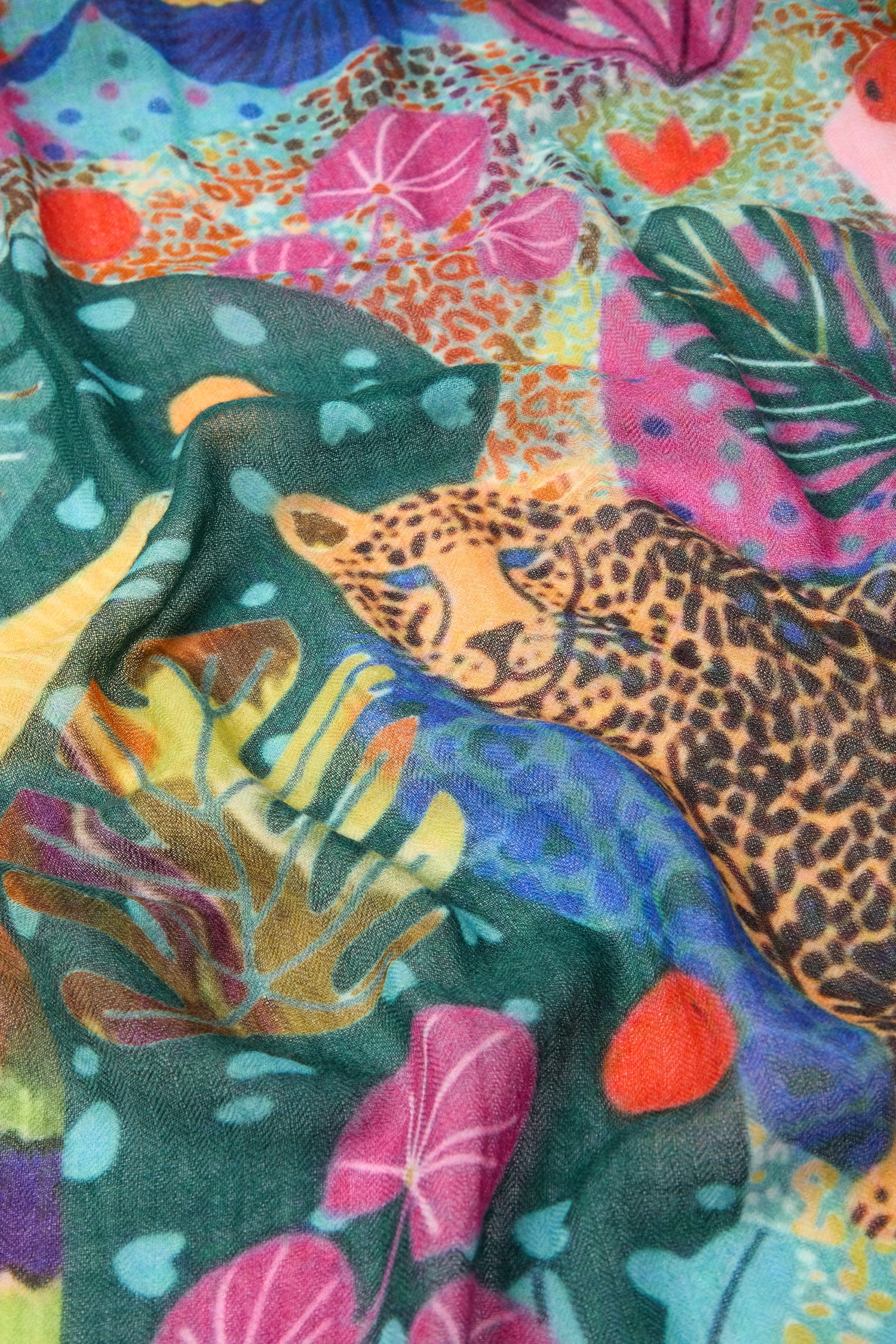 Close-up of the Jungle Print Wool Scarf, featuring a vivid depiction of a leopard and diverse tropical plant patterns. This vibrant accessory beautifully showcases the intricate flora and fauna of the jungle.