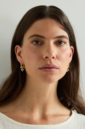 A woman with long brown hair wears Gold Vermeil Pearl Teardrop Hoops and looks directly at the camera against a plain light background.