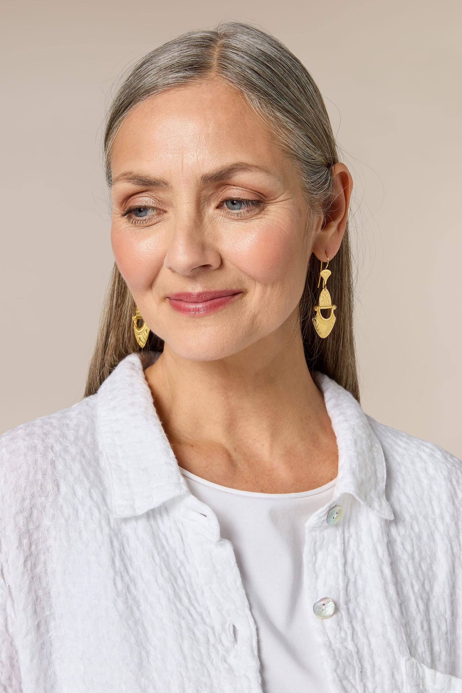 A woman wearing a white shirt and Engraved Gold Vermeil Tuareg Earrings.