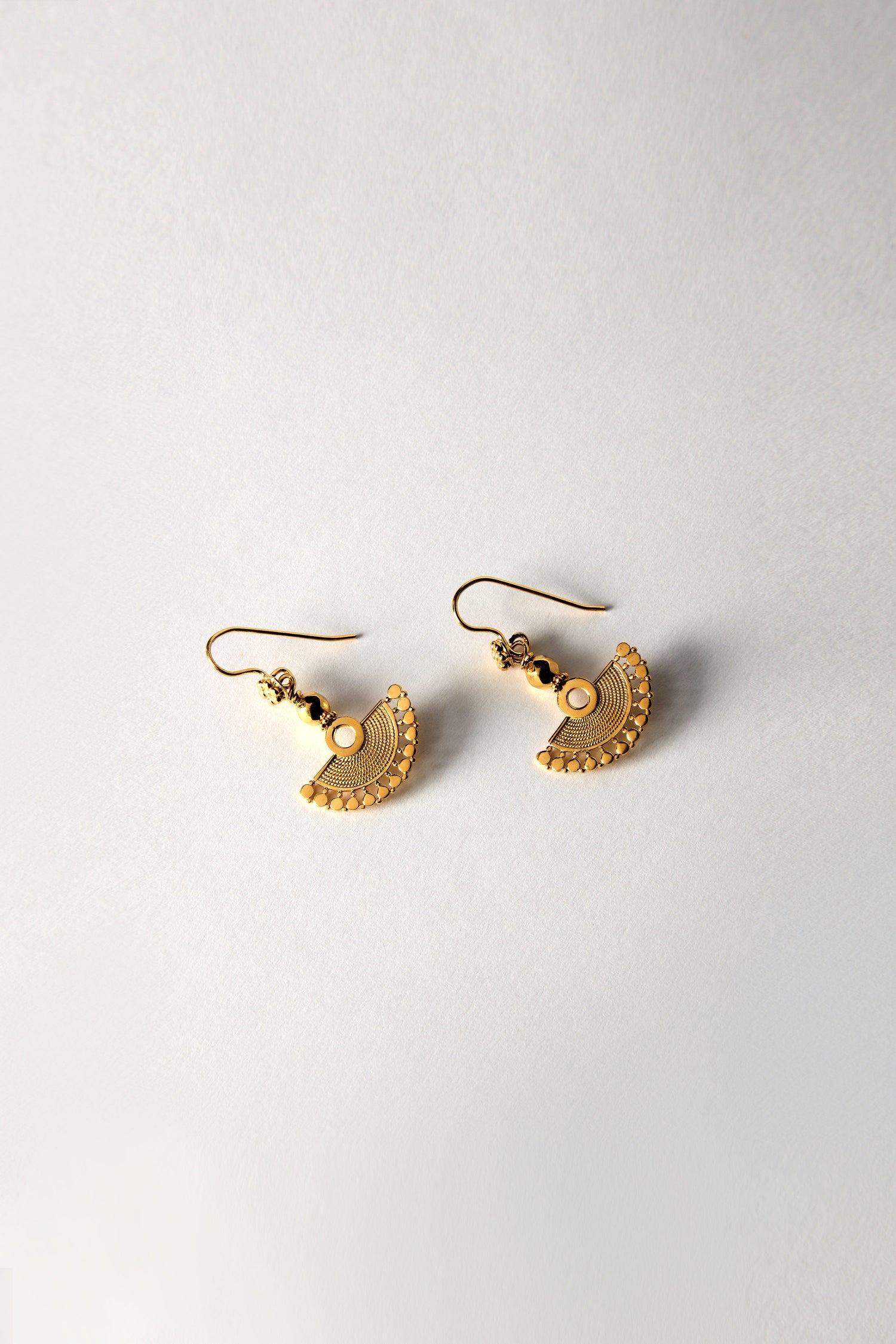 The Gold Vermeil Mini Fan Earrings, featuring intricate circular patterns, rest on a plain white background as part of an exquisite jewelry collection.