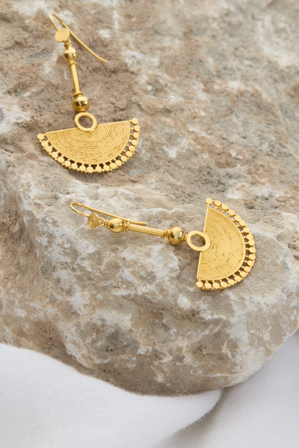 The 18ct Gold Vermeil Fan Earrings with intricate patterns rest on a textured stone surface, exuding bohemian elegance.