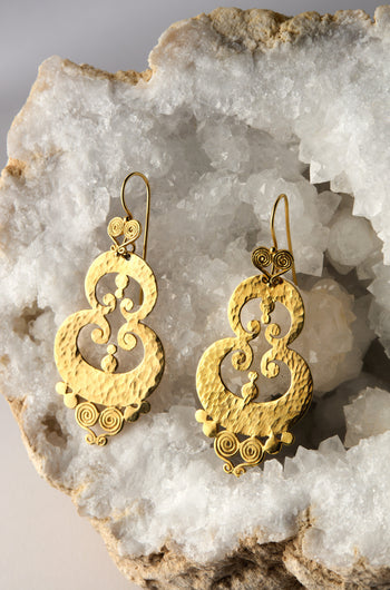 The Gold Vermeil Sumba Earrings feature a circular textured design with intricate filigree, displayed on crystalline rock.