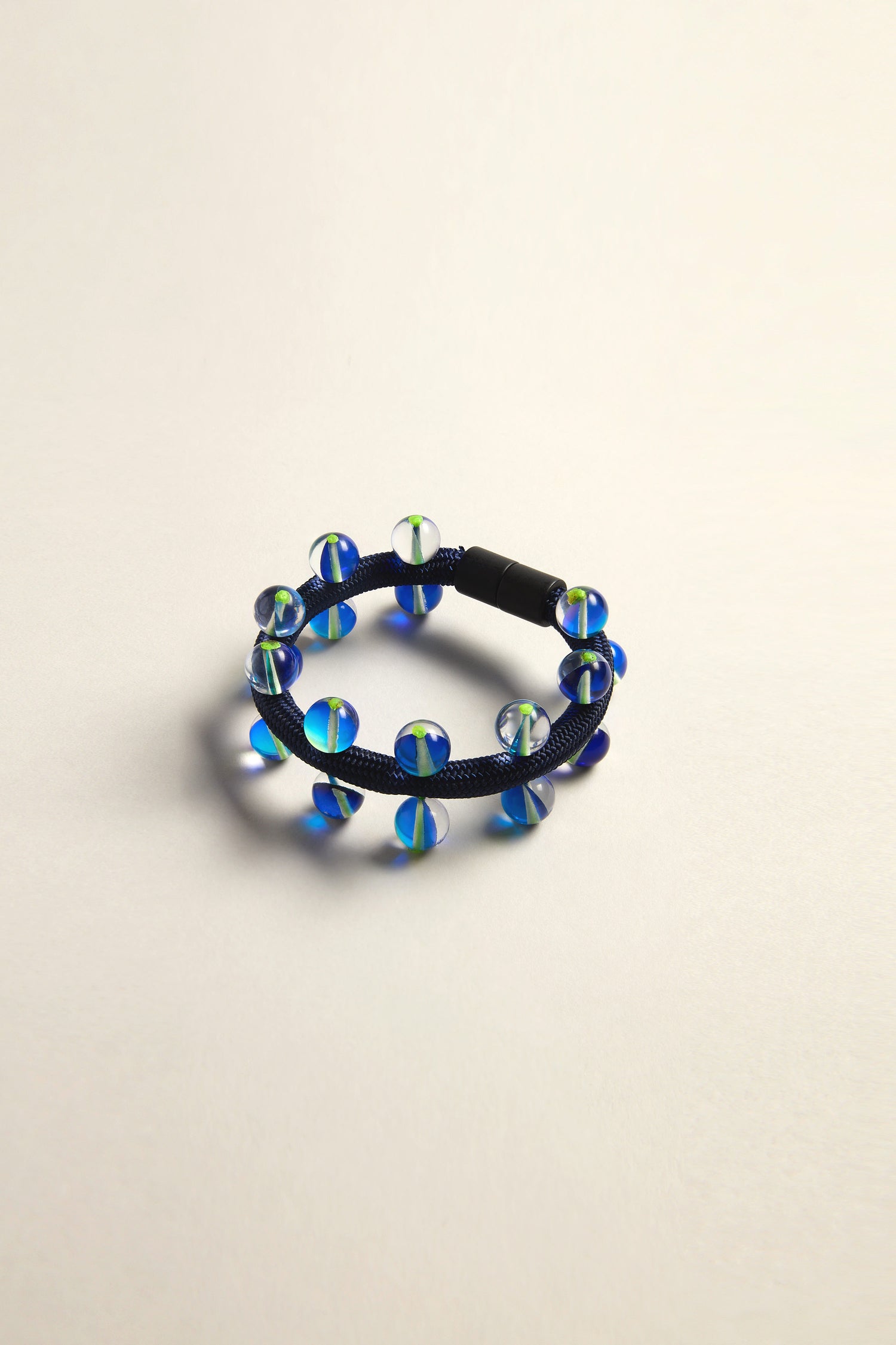 The Atmosphere Bracelet by Christina Brampti showcases modern elegance with round, translucent blue beads artfully arranged on a sleek surface.