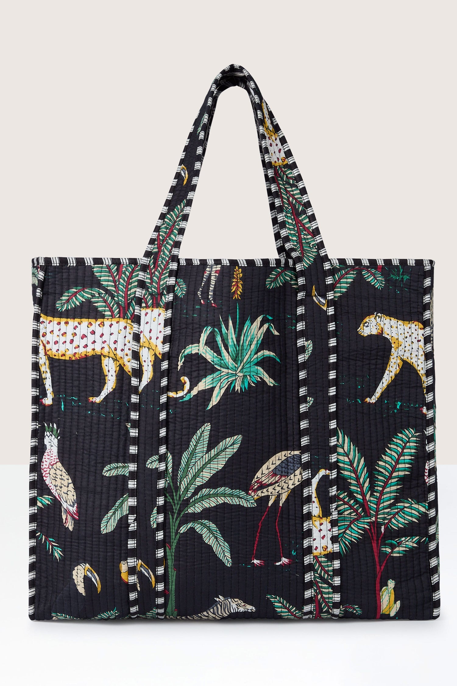 Introducing the Jungle Print Tote Bag from Conscious Yoga Collective: a black tote crafted from quilted fabric featuring a vibrant tropical print with animals and plants.