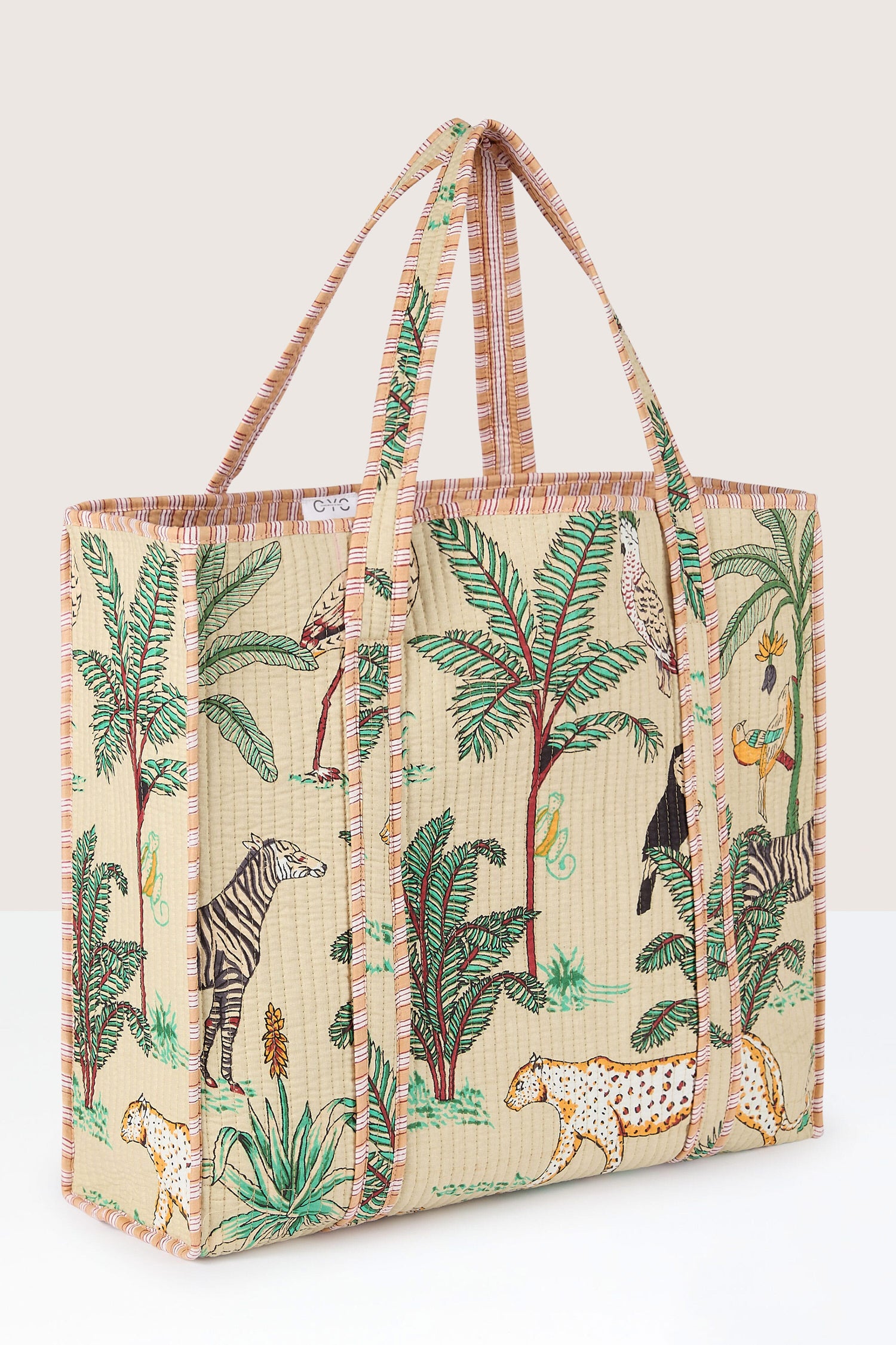 The Jungle Print Tote Bag features a colorful jungle print with animals, trees, and foliage on a large rectangular design. Made with quilted fabric, it also boasts two long, striped handles and a structured form, perfect for carrying your essentials to the Conscious Yoga Collective sessions.