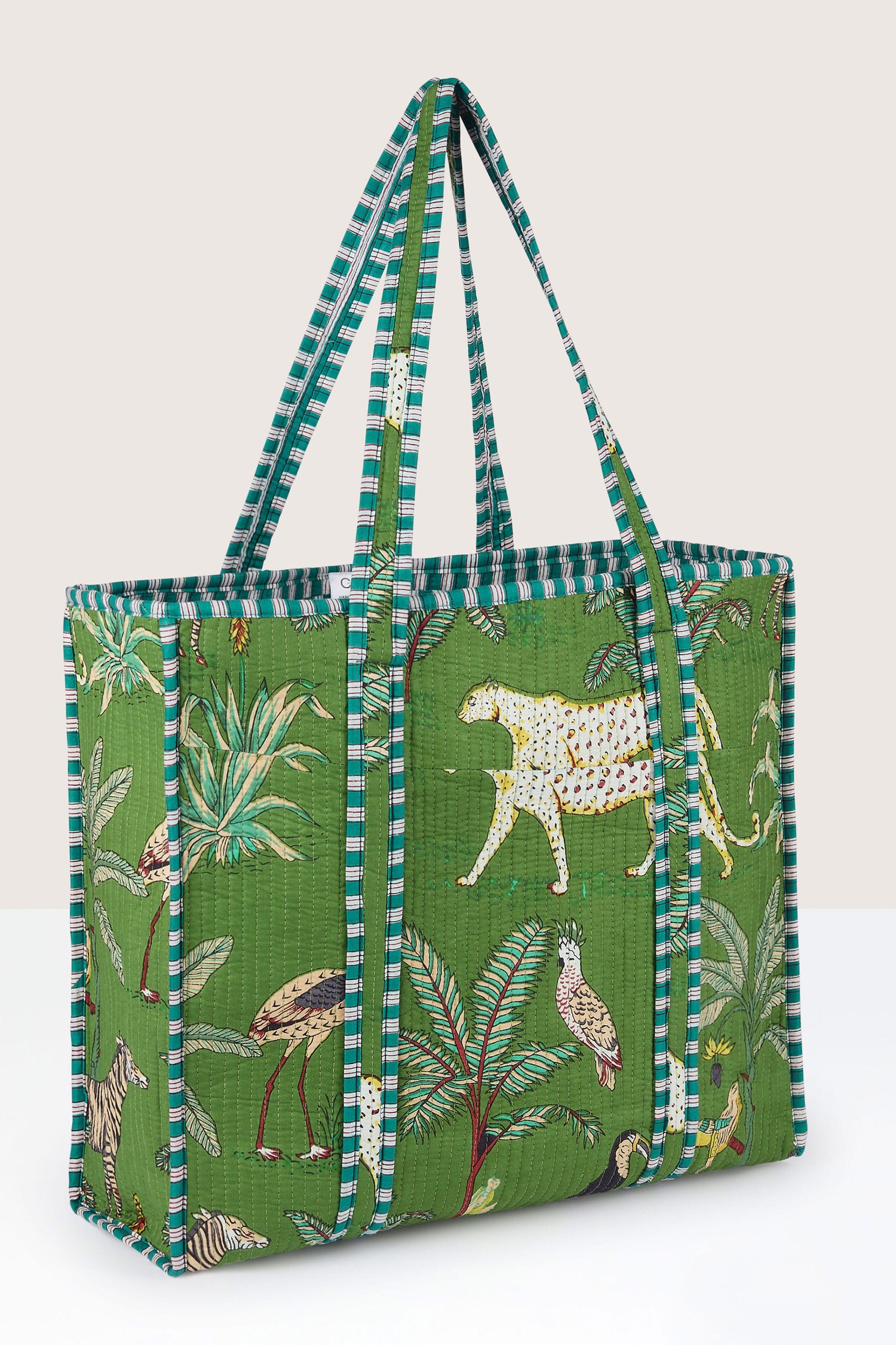 A large, consciously designed Jungle Print Tote Bag with striped handles and vibrant jungle-themed illustrations featuring cheetahs, birds, and plants. Quilted fabric adds an extra layer of durability and style for your everyday adventures.