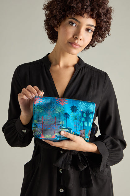 Person in a black dress holding a Large Jungle Pathway Velvet Bag featuring a tropical design.