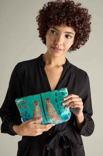 A person in a black dress holds the Large Sunshine Through My Window Velvet Bag adorned with a Cheetahs design, adding a touch of wild elegance.