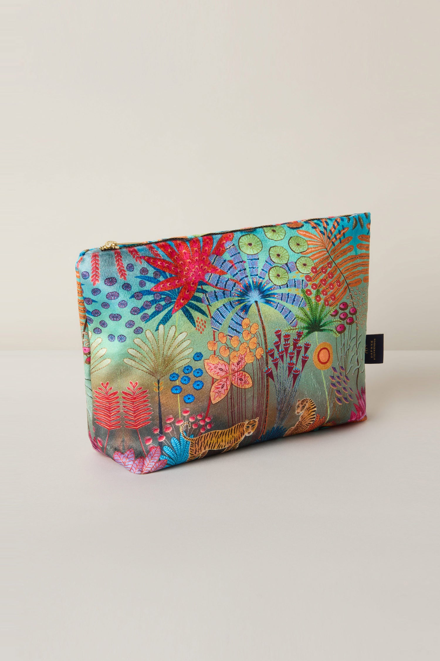 The Large Tale of Two Tigers Velvet Bag showcases a vibrant botanical pattern by Daphne Stephenson with colorful flowers and plants against a plain background.