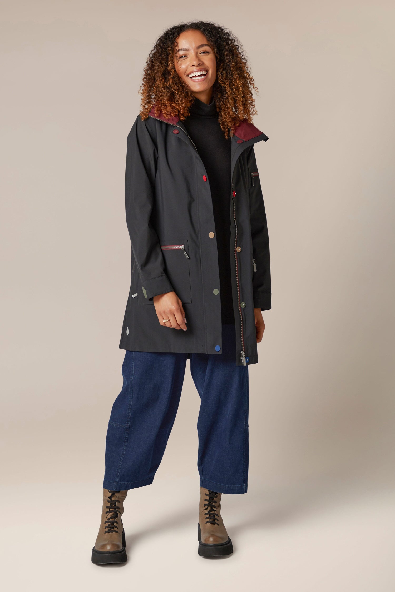 A woman wearing a 5 Pocket Hooded Rain Jacket and jeans.