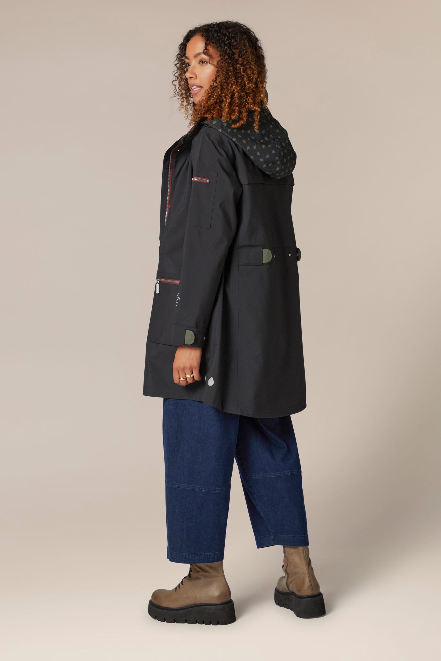 A woman wearing a 5 Pocket Hooded Rain Jacket and jeans.