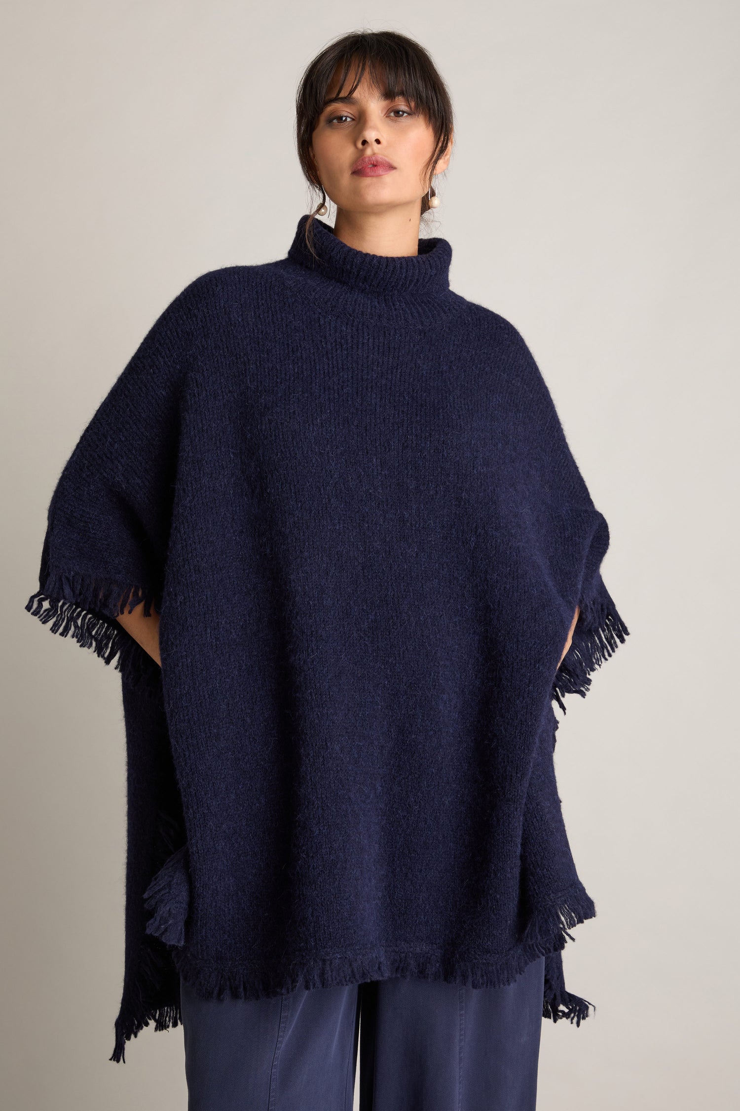 Person wearing a Cashmere And Alpaca Poncho stands against a plain light background, exuding luxury and comfort.